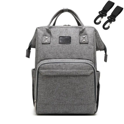 Light gray Baby Essentials-4 diaper bag with USB port and built-in sleeping crib, showing multiple compartments and adjustable straps.
