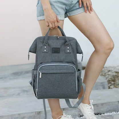 Baby Essentials-4 baby diaper bag with USB port and portable sleeping crib, featuring multiple compartments and stylish design.